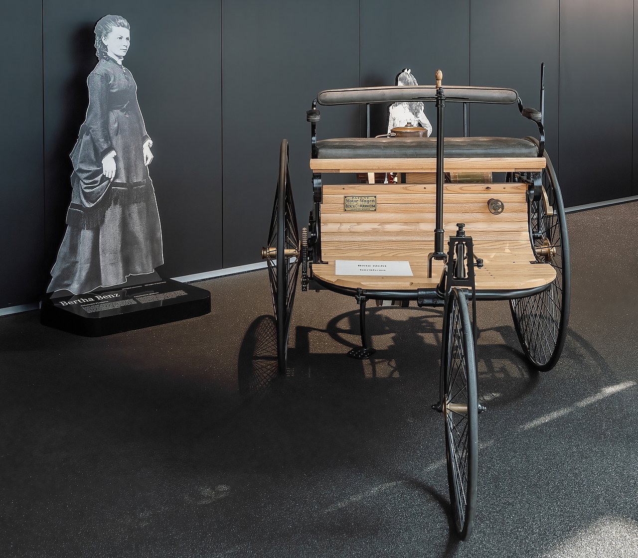 Benz Patentmotorwagen, im Hintergrund Fotografie von Bertha Benz. Bildrechte: shutterstock